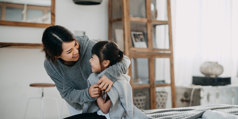 Mother putting a coat around her daughter 